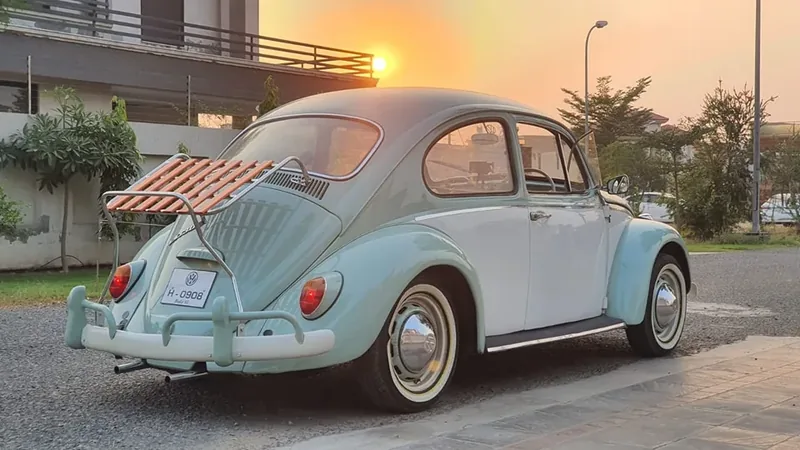 Rear three-quarter sunset view of a pale Volkswagen Beetle with a deck-lid rack