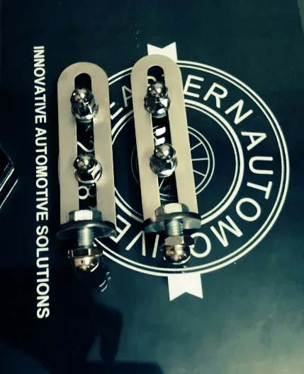 Two silver deck-lid rack mounting straps with bolts on a dark mat