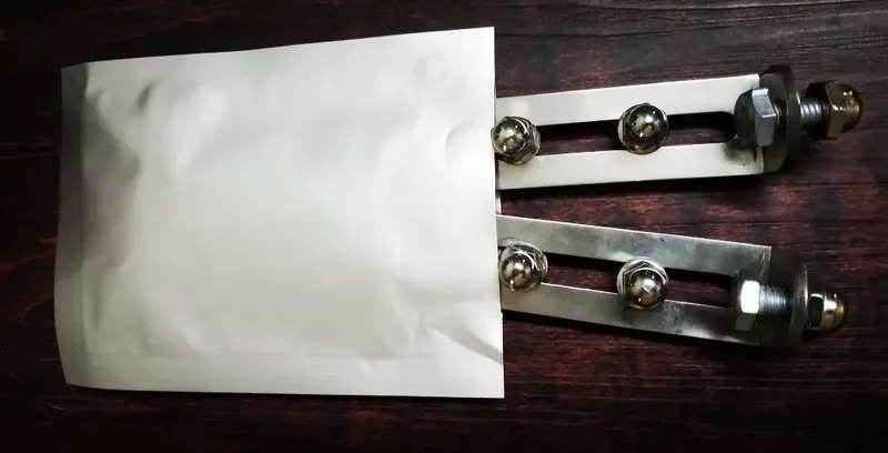 Two silver rack mounting straps beside a folded white cloth on a wooden surface