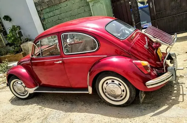 Side view of a red Volkswagen Beetle with a fitted red-slatted deck-lid rack