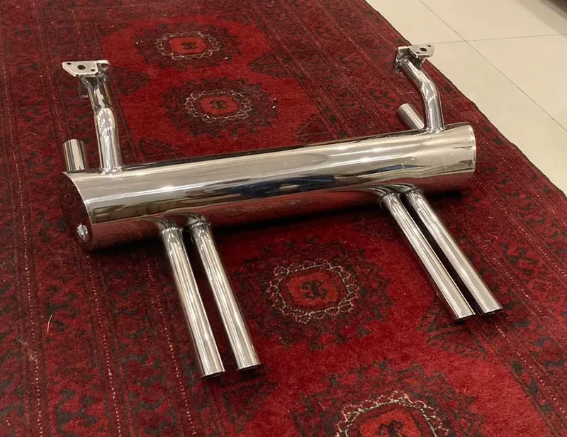 Complete chrome four-tip exhaust assembly displayed on a patterned red rug