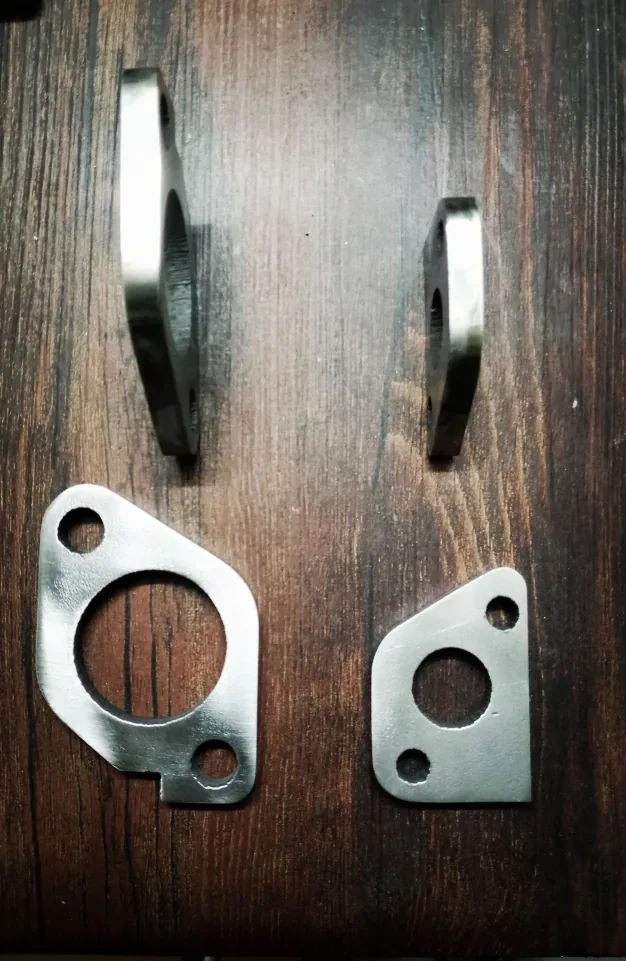 Four metal flange plates shown face-on and edge-on on a wooden surface