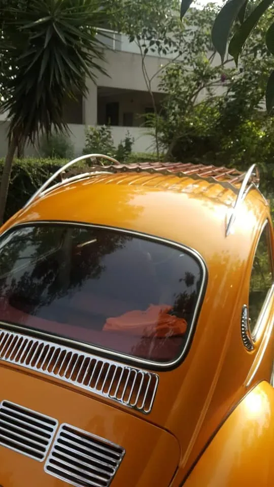 Red-slatted roof rack fitted above the rear window of an orange Volkswagen Beetle