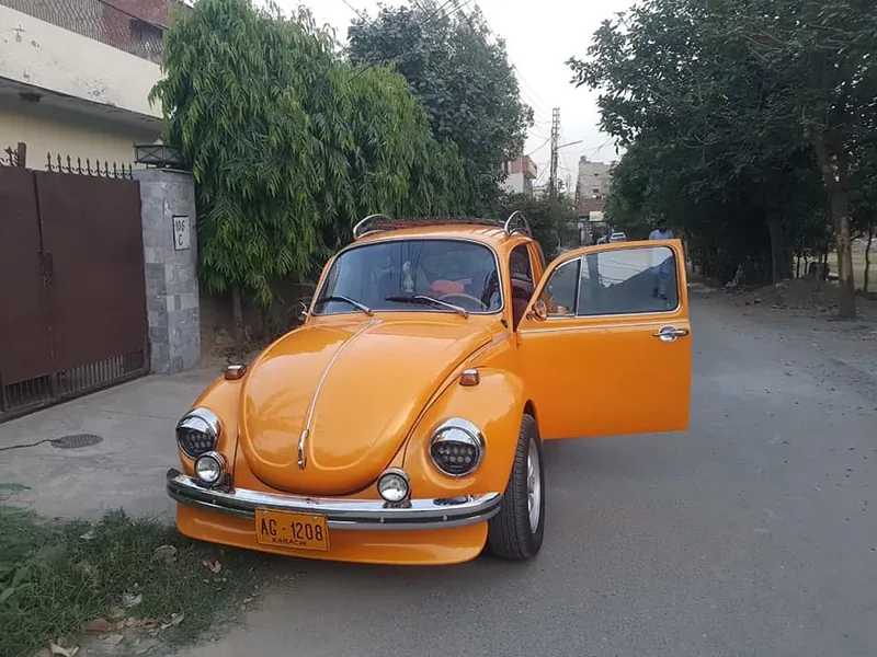 Orange Volkswagen Beetle with an open door and a fitted red-slatted roof rack
