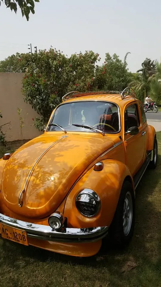 Front view of an orange Volkswagen Beetle with a roof rack above the windshield