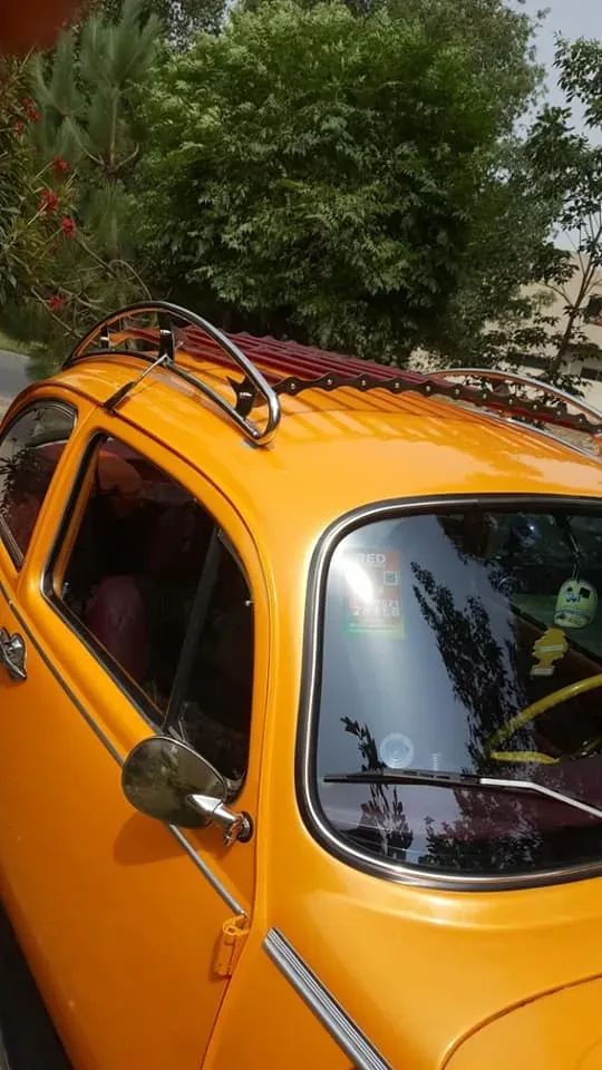 Side-window view of a red-slatted roof rack fitted to an orange Volkswagen Beetle
