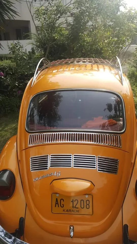 Rear view of an orange Volkswagen Beetle with a roof rack above its rear window