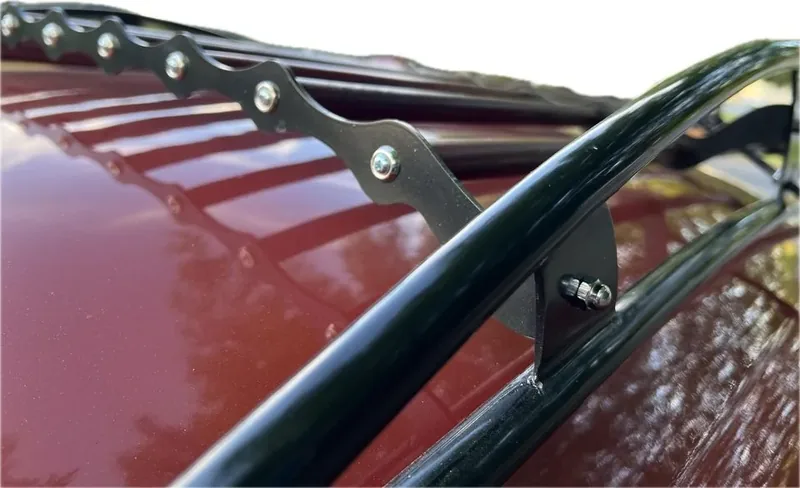 Bolted black roof-rack bracket beside red slats on a red Volkswagen Beetle