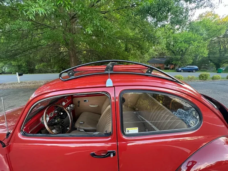 Side view of a red Volkswagen Beetle with a fitted black-and-red roof rack