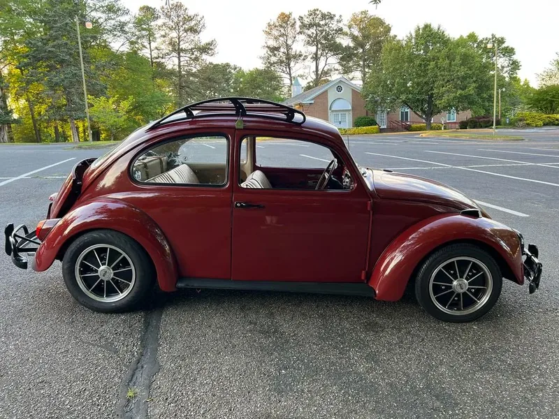 Full side profile of a red Volkswagen Beetle with a fitted roof rack