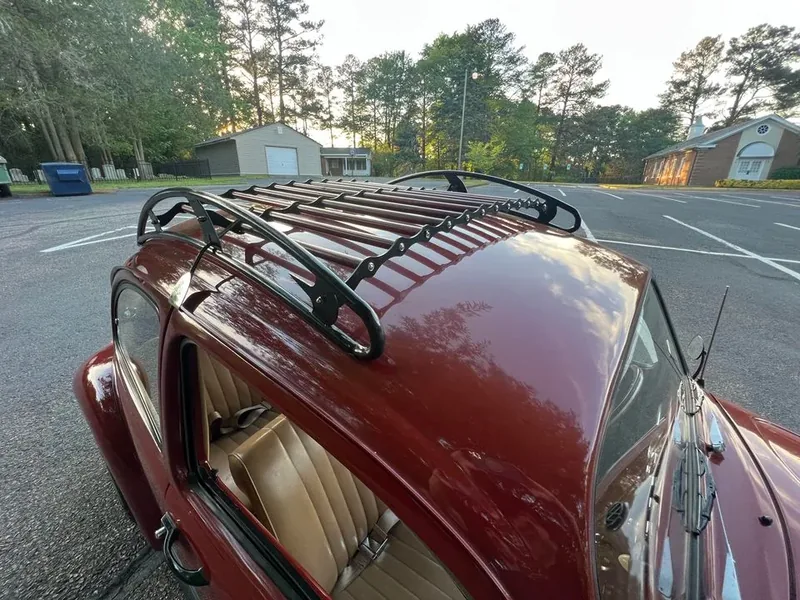 High-angle view of a black-and-red roof rack over a red Volkswagen Beetle side window