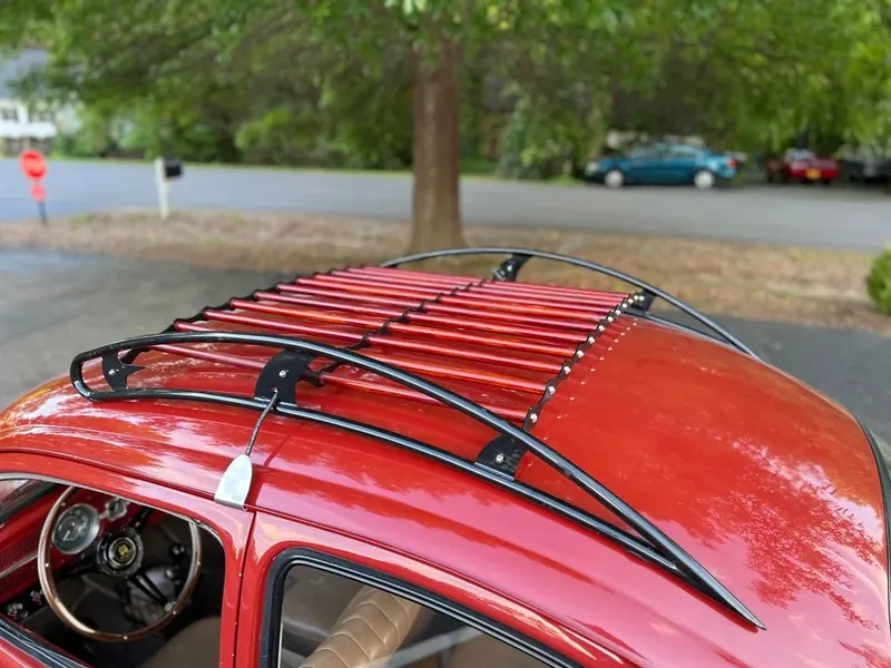 Red-slatted roof rack viewed above the open side window of a red Volkswagen Beetle