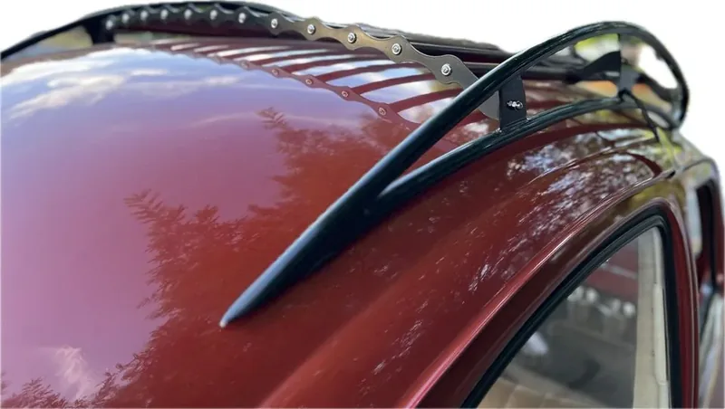 Black roof-rack rail and scalloped slat strip fitted to a red Volkswagen Beetle