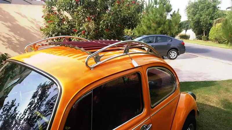 Chrome-and-red roof rack fitted above the side windows of an orange Volkswagen Beetle