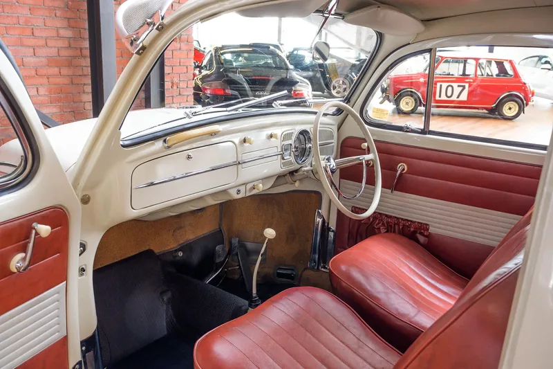 Cream dashboard and red seats inside a white Volkswagen Beetle