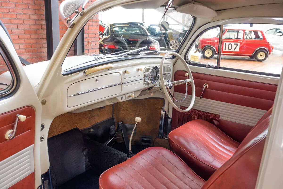 Cream dashboard and red seats inside a white Volkswagen Beetle