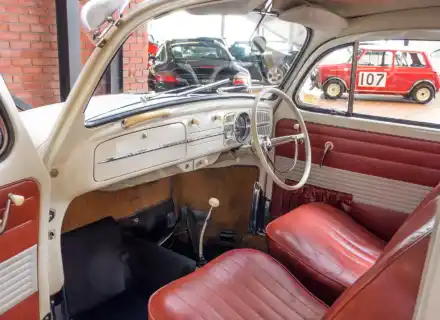 Tableau de bord crème et sièges rouges à l'intérieur d'un Volkswagen Beetle blanc