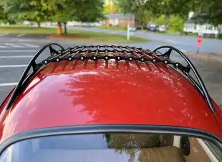 Galerie de toit noire et rouge centrée au-dessus d'une lunette arrière rouge Volkswagen Beetle