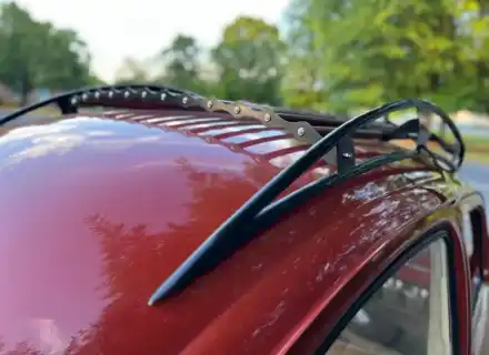 Rail latéral de galerie de toit noir longeant le toit d'une Volkswagen Beetle rouge