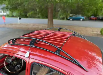 Galerie de toit à lattes rouges vue au-dessus de la vitre latérale ouverte d'une Volkswagen Beetle rouge