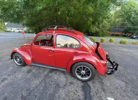 Vue de trois quarts arrière d'une Volkswagen Beetle rouge avec une galerie de toit installée
