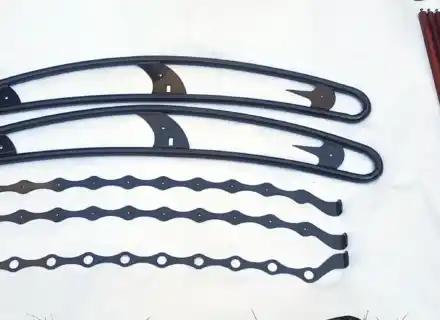 Rails de cadre noirs, supports festonnés et lattes brun rougeâtre disposés séparément